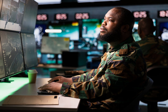 Soldier looking at equipment displays in war room housing operational missile defense system designed to intercept ballistic rockets. Intelligence corps expert using radar systems