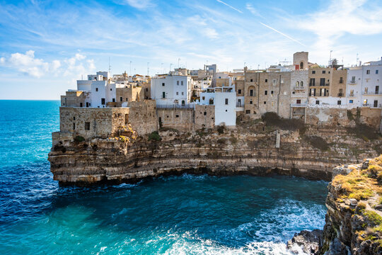 Stunning view of white coastal buildings perched on rugged cliffs above turquoise sea in Polignano al Mare town, Apulia, Italy