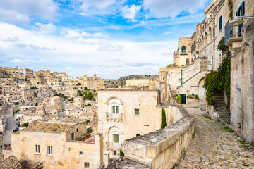 Obraz premium Narrow cobblestone path winding through historic stone houses and terraces, Apulia, Italy