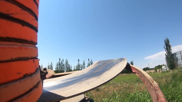 Close-up of an automatic clay pigeon thrower loaded with orange targets, ready to launch disks into the field for trap shooting sport practice on a sunny summer day.