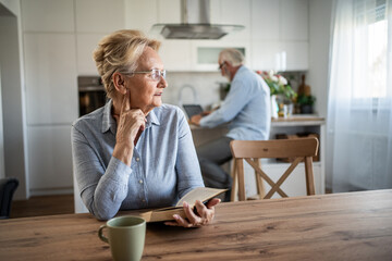 Senior woman contemplating while reading in kitchen