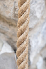natural-fiber rope is captured in a tight vertical close-up, showcasing the heavy twisting. colored rock background. The rough, fibrous texture , strength nautical applications.