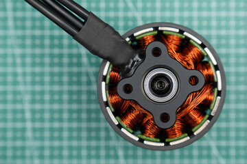 brushless FPV drone motor's central structure, showcasing the intricate copper coil windings around the stator. black mounting plate and bearing are visible at the center