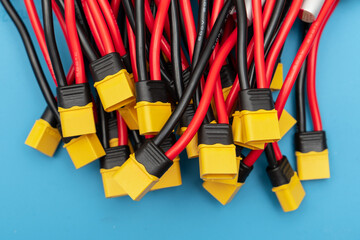 heap of yellow XT60 power connectors with red and black silicone wires on blue background. high-current connectors link the FPV drone battery to the electronic
