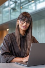 middle eastern woman working on her laptop, focused at work, corporate environment