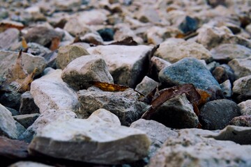 ​a detailed low angle close up of a pile of coarse gray and white gravel and pebbles scattered...