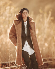 Elegant fashionable lady in brown fur coat over classic business suit on background of country...