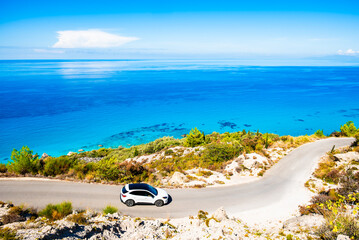 Car driving on winding road to sea coast and beautiful Avali beach, Lefkada island, Greece
