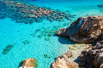 Rocks and stones in crystal clear turquoise sea water of Agios Nikitas beach, Lefkada island, Greece