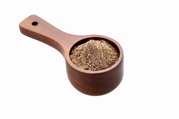Ground black pepper in a measuring spoon on a white background - Piper nigrum