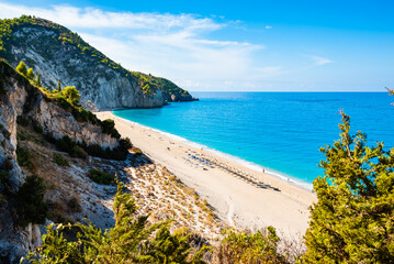 View of cliffs with green pine trees and Milos beach from high vantage point, Lefkada island, Greece