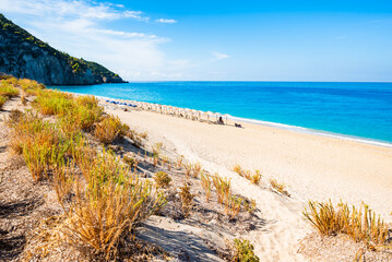 Green plants in sand dune and view of amazing Milos beach, Lefkada island, Greece