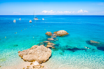 Unidentified man snorkelling among rocks in crystal clear turquoise sea on Agios Nikitas beach, Lefkada island, Greece