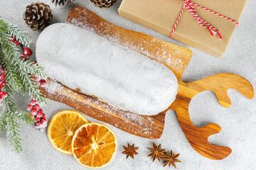 Traditional Christmas Stollen, sweet fruit loaf with sugar icing on wooden board and festive decor