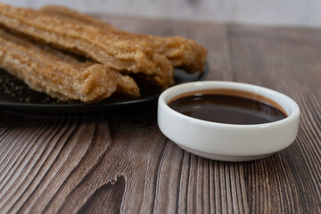 Churros on a wooden table with chocolate. Mexican food