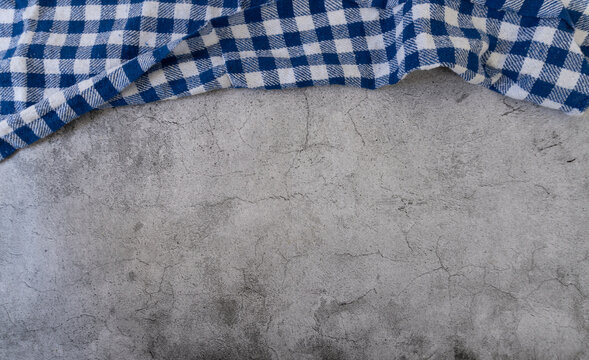 Blue and white checkered tablecloth on top of a gray surface. Kitchen or restaurant background