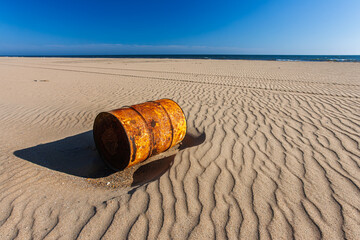 Rusted oil drum on Mazagon beach under clear blue sky