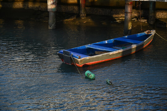 old abandoned wooden fishing boat, sinking in dark river water, time and decay small vessel half submerged, rustic nautical texture, vertical top-down view solitary boat tied with rope