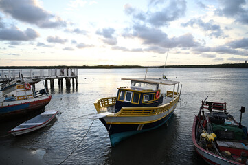 Obraz premium fishing boats moored at potengi river, natal brazil, sunset light on water traditional brazilian fishing vessel, coastal life and maritime culture small and large boats at low tide