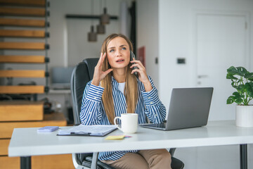 Obraz premium Stressed woman talking on phone working online from home office