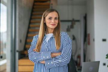 Confident businesswoman smiling with arms crossed in modern office