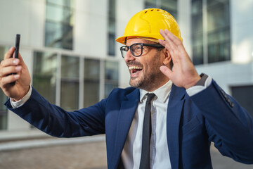 Engineer in hard hat having video call on smart phone