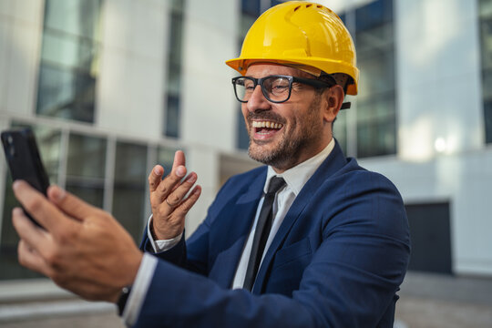 Engineer in hard hat having video call on smart phone - Powered by Adobe