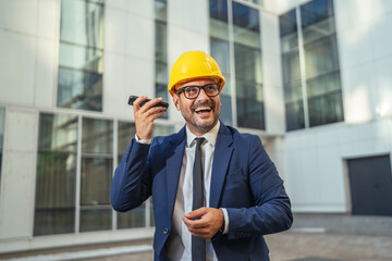 Happy engineer in suit talking on phone at construction