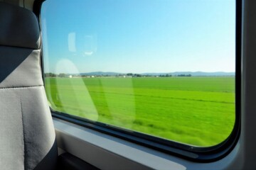 Obraz premium Coach Window View Seat and Scenic Vista A close up view from an empty coach seat, focusing on a clean, large window. Through the window, a vibrant, slightly blurred scenic landscape of rolling green