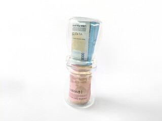 The image shows several stacks of rolled banknotes wrapped tightly in transparent plastic. Each stack consists of a blue banknote on top and a pink banknote beneath it