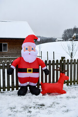 Inflatable Santa and reindeer Christmas decorations in snowy yard