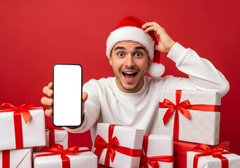 Excited Man in Santa Hat Holding Blank Phone Screen Amid Gifts