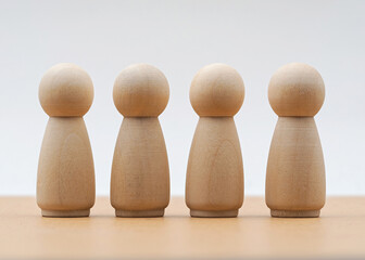 Wooden figures arranged in a row on a smooth surface with natural light illuminating the scene