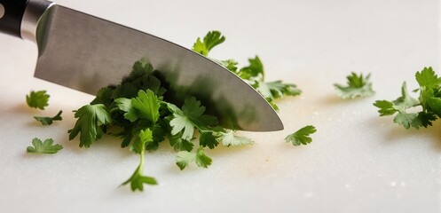 Close-up of a knife finely chopping fresh coriander on a clean cutting board