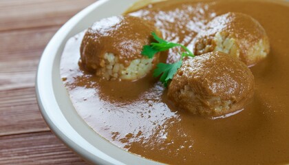 Close-up of delicious, home-style meatball dish in rich, savory sauce with a garnish of fresh herbs, perfect for a comforting meal