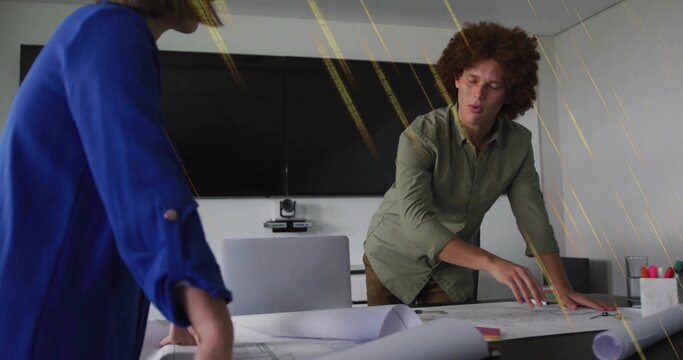 Pointing, man in green shirt leaning over plans at conference table with colleague in blue blouse - Powered by Adobe