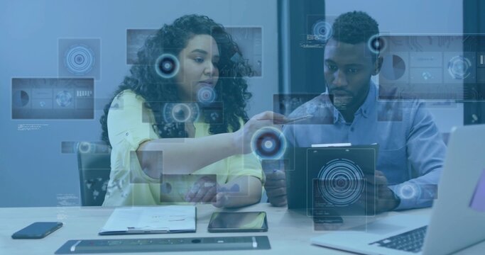 Pointing and explaining, pair in yellow blouse, light blue shirt holding tablet with AR graphics