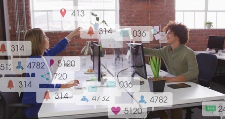 Reaching coworkers wearing blue blazer and green shirt, exchanging file at modern office, monitors