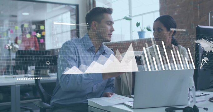 Reviewing colleagues in blue shirt and neutral blouse with jacket, viewing laptop charts at office