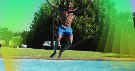 Jumping shirtless man wearing blue swim shorts soaring into pool at home, with rope across torso