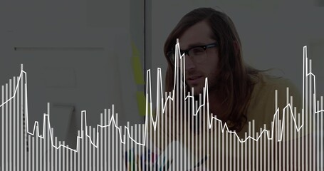 Analyzing man wearing glasses and mustard-yellow shirt at office desk with screen, markers, overlay