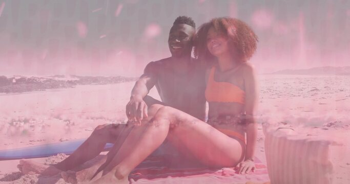Sitting couple smiling on towel on sandy beach, wearing swimwear, surfboard and bag nearby - Powered by Adobe