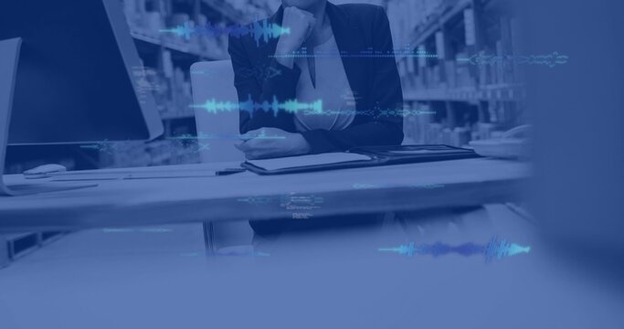 Sitting woman wearing dark blazer and blouse, resting chin at office with screen, folder, waveform - Powered by Adobe