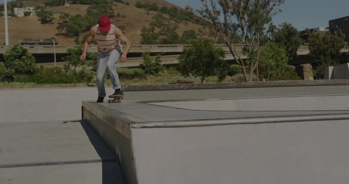 Leaning skateboarder dropping in from ledge at skatepark in red cap with skateboard, copy space