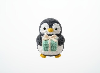 Handmade crochet penguin holding a gift box with a bow on a white background, perfect for holiday or Christmas themes