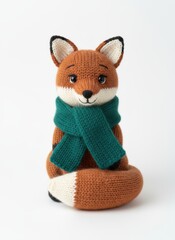 Handmade knitted fox toy wearing a green scarf, sitting on a white background, showcasing cozy and cute craftsmanship