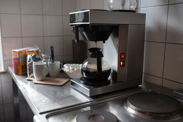Coffee maker with illuminated brewing chamber actively preparing fresh coffee on kitchen surface