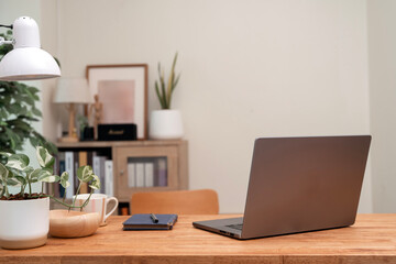 Back view of a modern laptop resting on a wooden desk in a bright and comfortable home office, ready for work.
