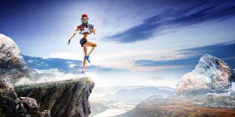 American football players in action high in the mountains on the edge of a cliff. Sports concept. Extreme sports moment. Panorama. Cliff. American football players in rock