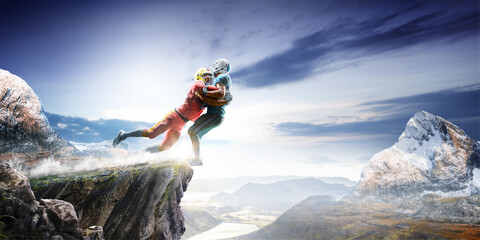 American football players in action high in the mountains on the edge of a cliff. Sports concept. Extreme sports moment. Panorama. Cliff. American football players in rock